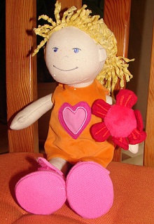 a fabric doll with blonde hair, an orange dress and pink shoes