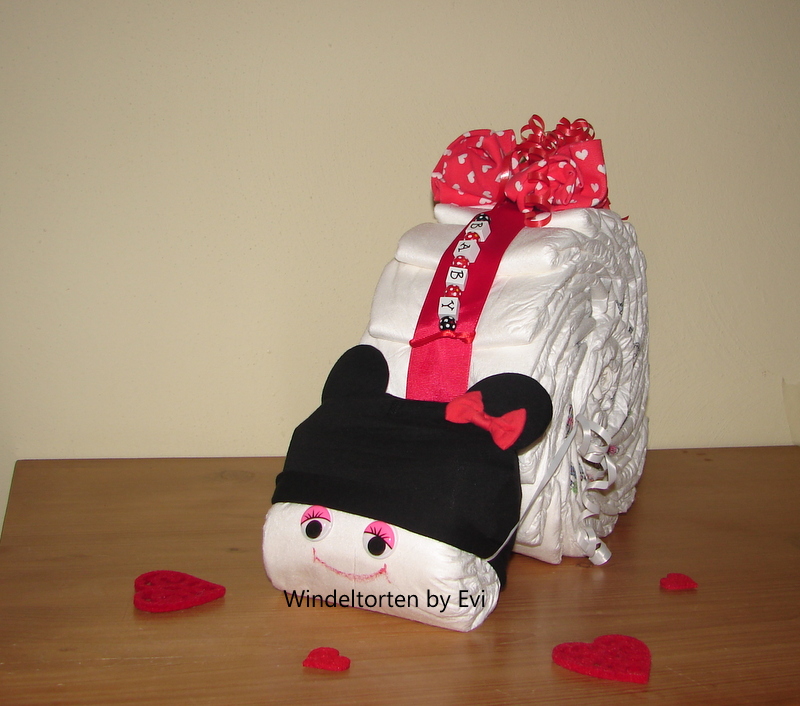a diaper mouse cake wearing a black Mickey Mouse hat and also decorated with red polka dot ribbon
