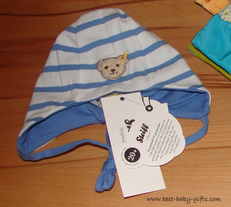 a blue and white baby hat with the iconic Steiff teddy bear logo on it
