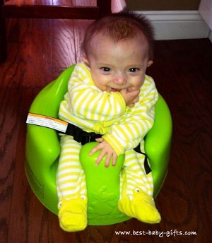 a happy baby boy in a green Bumbo floor seat