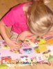 toddler girl sitting on floor looking at a colorful book