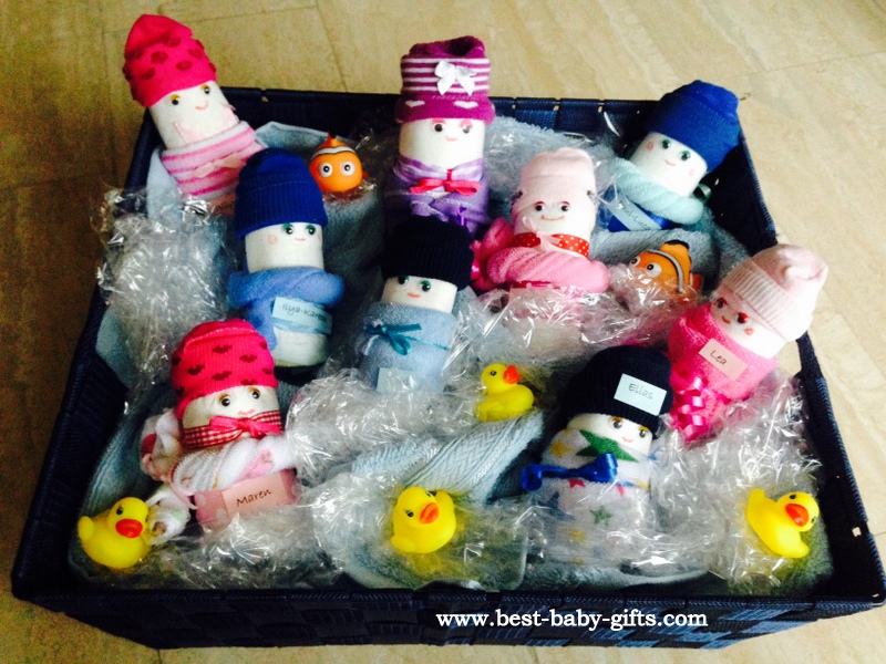 9 diaper babies, orange fishes and yellow squirting ducks in a large black tub, looking like babies in a swimming pool, water simulated with plastic foil