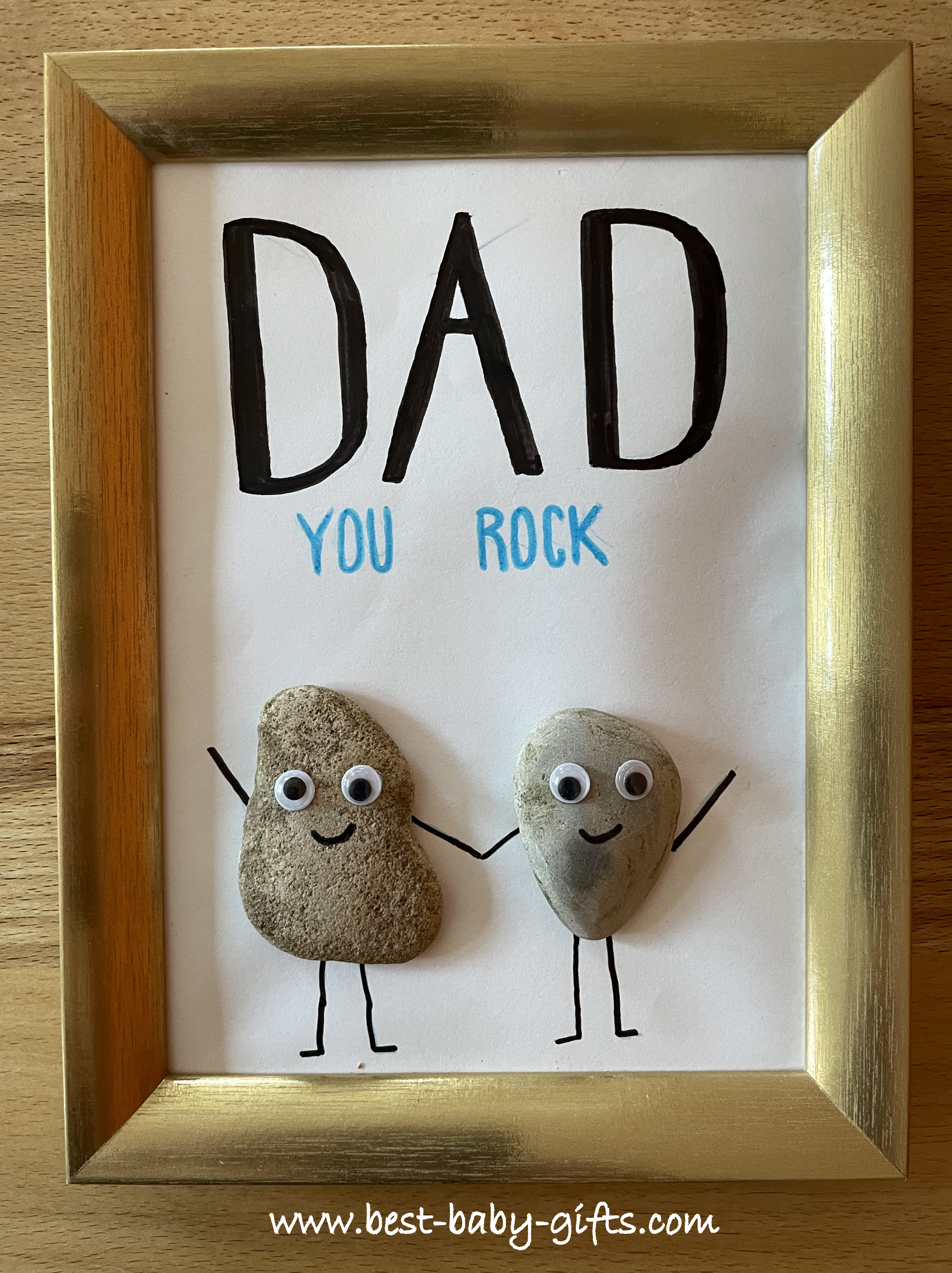 a cute DIY gift in a picture frame made of stones, picturing dad and child saying "Dad - you rock"
