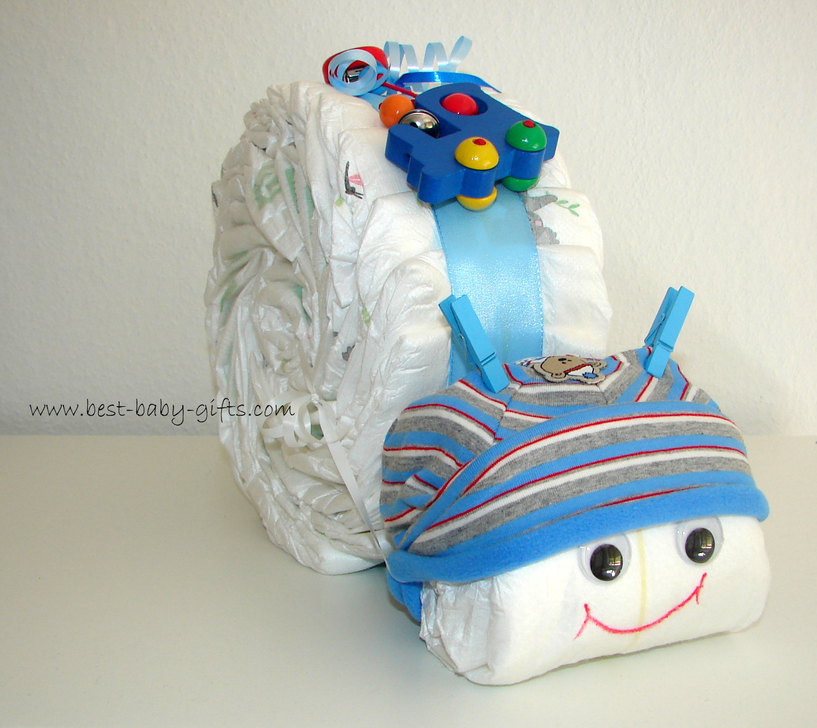 a boy diaper snail in blue with a baby hat (bule/white/red stripes) and a little wooden train toy on top