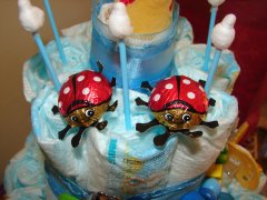 two little red chocolate bugs sitting on a diaper cake