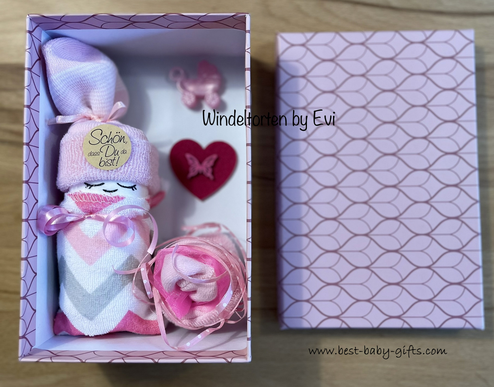an open pink gift box with a diaper baby inside.