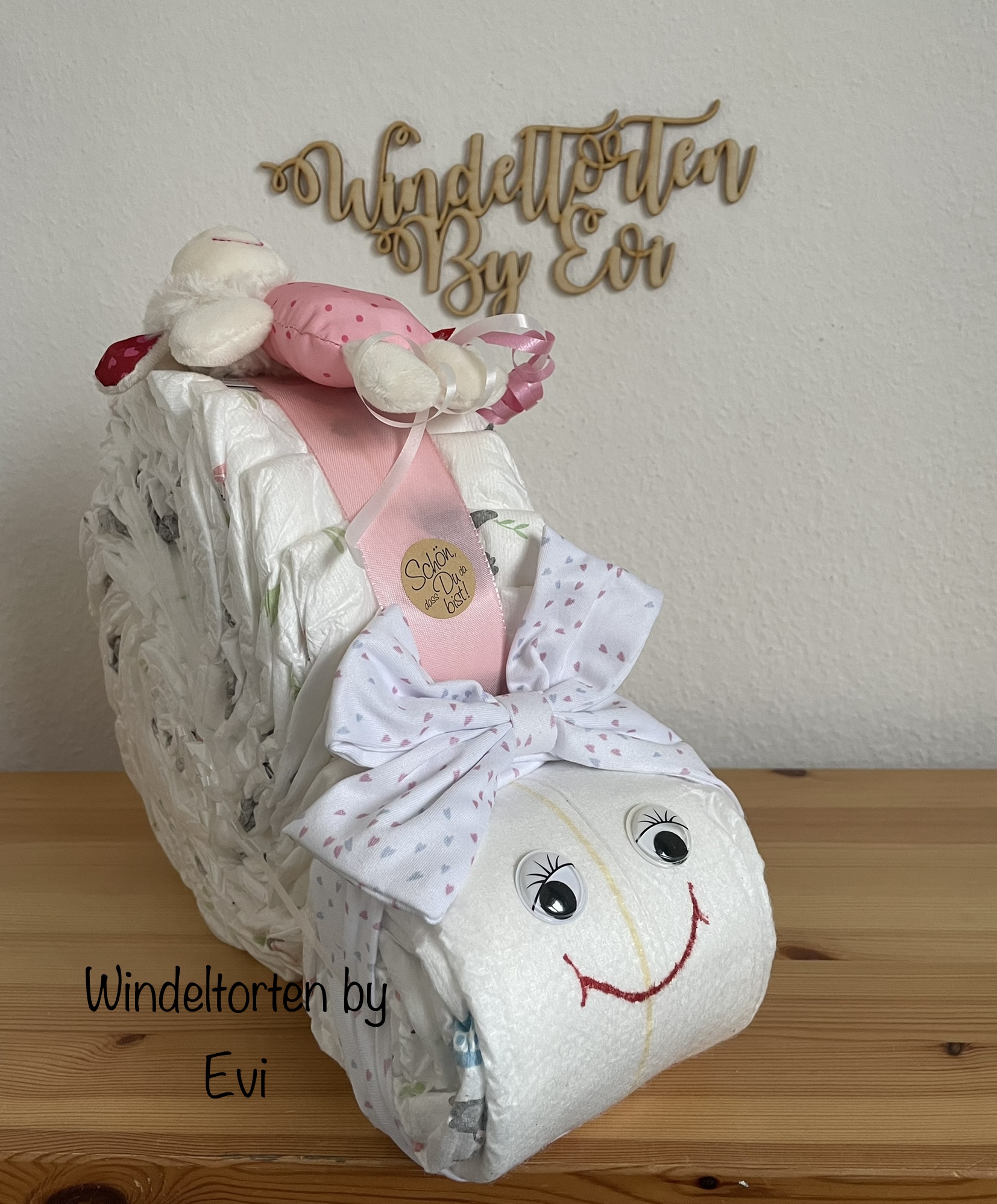 a diaper snail diaper cake for a baby girl with an adorable headband and a rattle toy on top, mainly white and pink colors