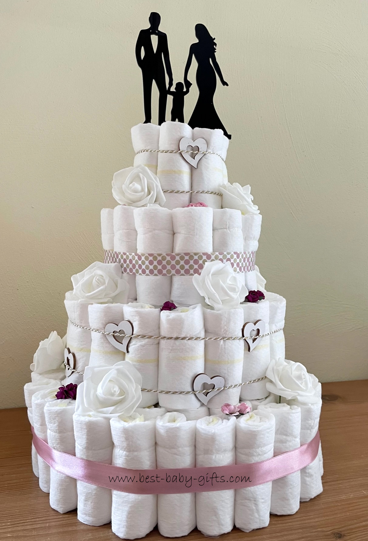 a wedding diaper cake in white with a wedding couple and a baby on top