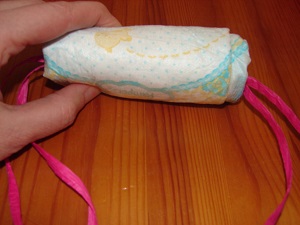 fingers with fully rolled diaper with ribbon inside