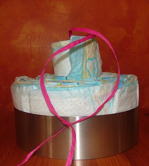cake setting ring with diapers and last diaper with ribbon inside inserted on top but still sticking out