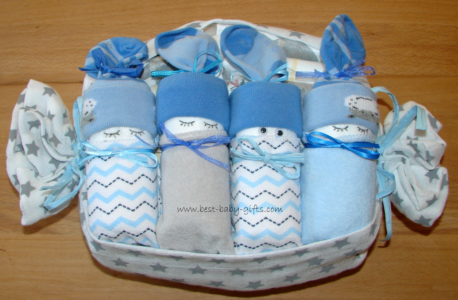 4 blue diaper babies made with organic baby socks and wash cloths wrapped up in a eco-friendly white burp cloth with grey stars