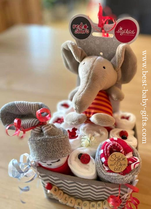 a little gray basket filled with diapers,a cuddly elephant and a sleeping diaper baby