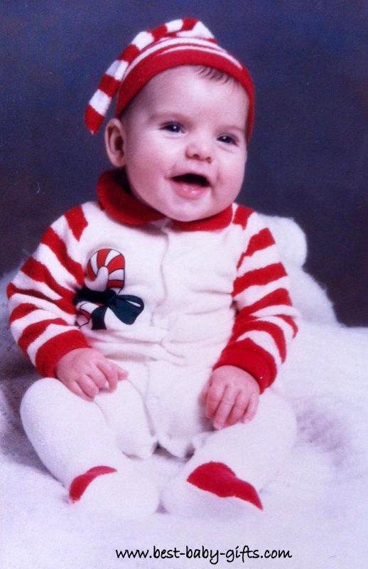 a laughing baby in a Christmas outfit, wearing a red and white Xmas hat