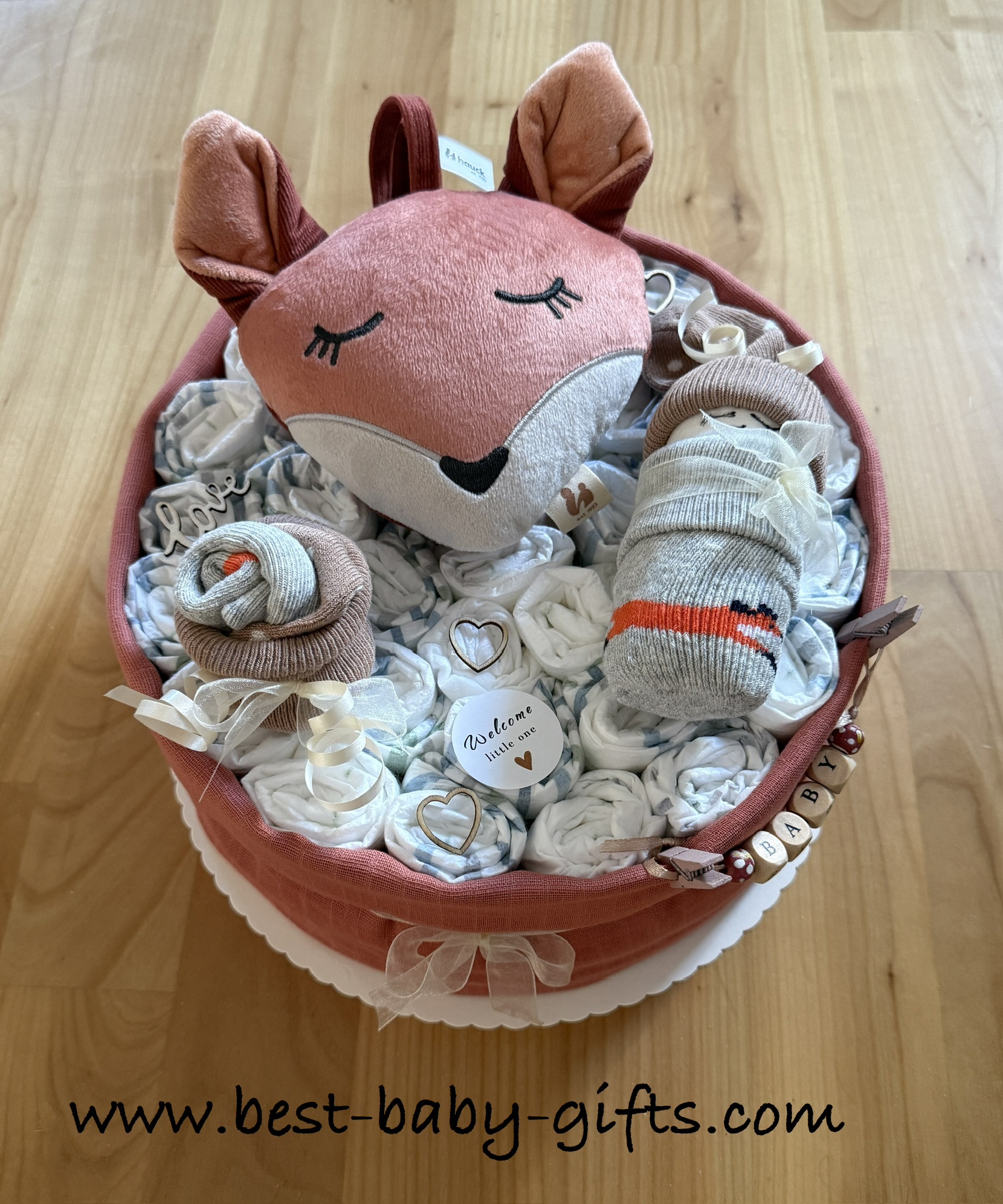 fox diaper cake, round 1-tier diaper cake with a large fox head (musical toy) and a diaper baby made with socks that have a fox design, neutral colors