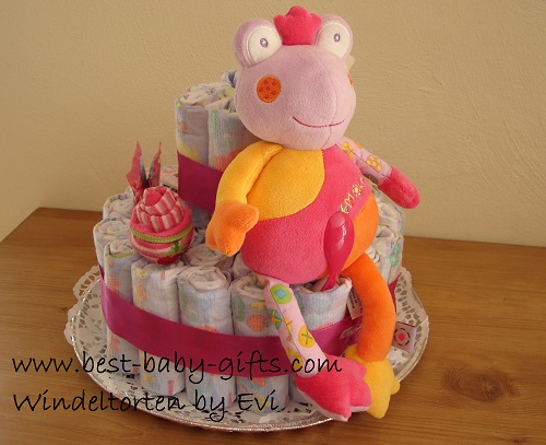a small diaper cake with a pink frog plush toy sitting on it