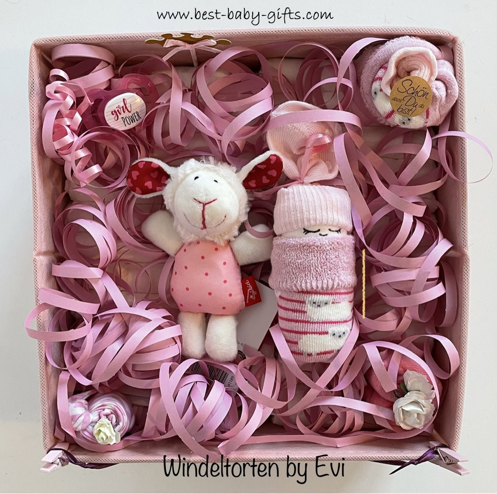 a big pink box filled with diapers, pink paper streamers, a sheep and a diaper baby, all in pink
