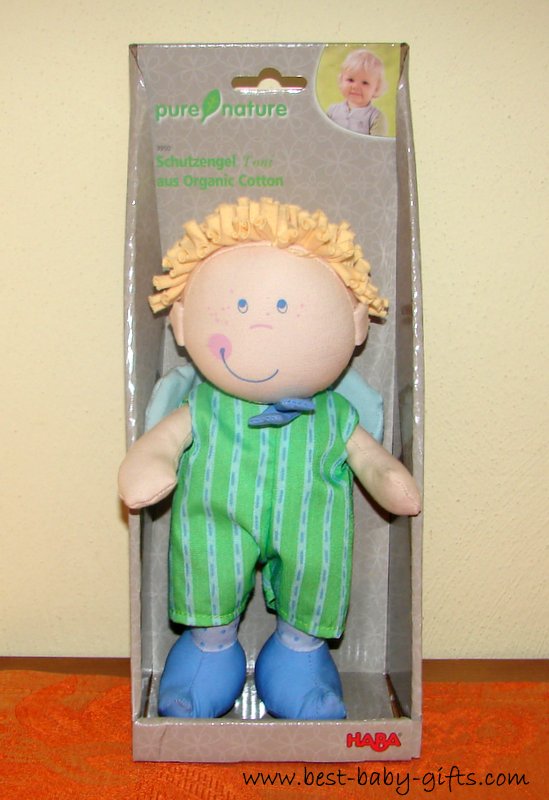a winged blonde boy dolly wearing a green bodysuit and blue shoes standing in a gift box