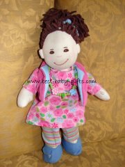 soft doll with brown hair in a pony tail, a pink dress with flowers and blue shoes