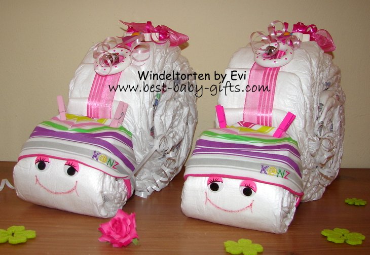 2 identical diaper snails side by side, they have rainbow color accessories such as the striped baby hats they are wearing and they are very colorful