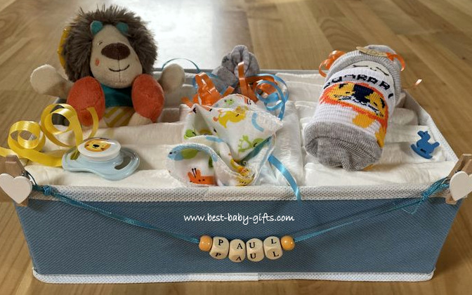 a blue box, holding lots of diapers, a plush lion, a diaper cake, a pacifier and personalized with the name "Paul"