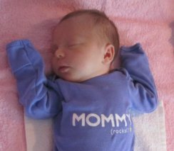 sleeping baby girl wearing a lilac onesie saying 'Mommy rocks'
