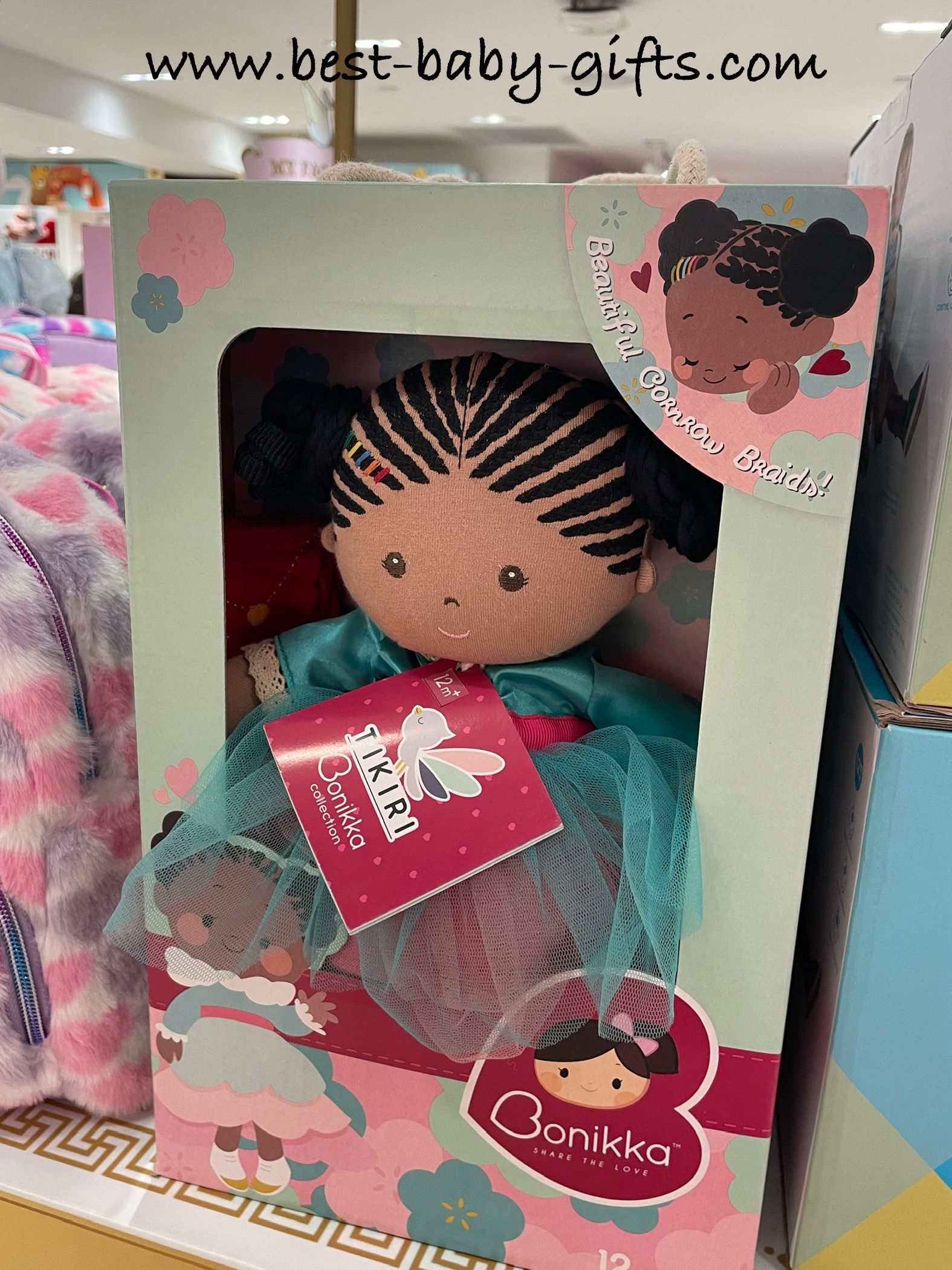 an adorable soft doll with dark colored cornrow style hair and sweet facial features that are embroidered. Her dress is aqua and pink made from tulle fabric