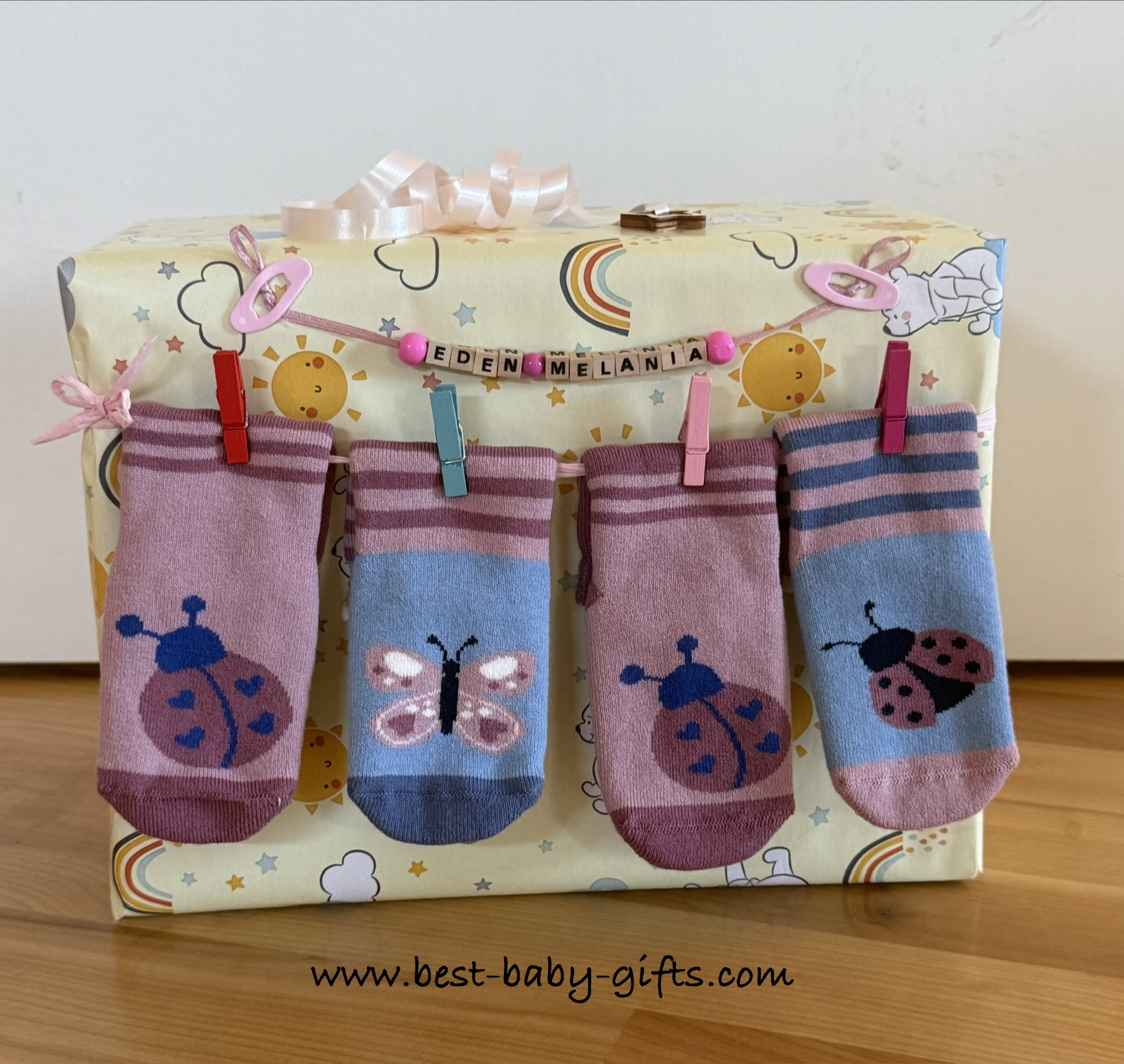 diaper pack wrapped nicely: diapers are in a box wrapped with wrapping paper. Some baby socks are fixed to make it look like a clothes line - personalized with wooden letters "Eden Melania"