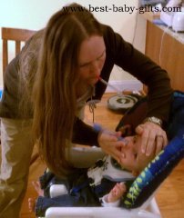 a mother leaning over her toddler applying a snotsucker