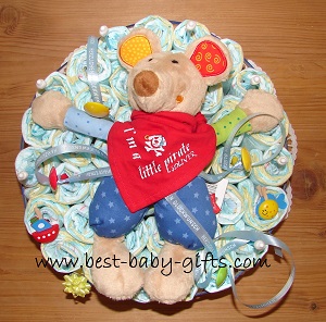 a base of diapers with a colorful cuddly mouse on top, the mouse wears a bandana saying 'I'm a little pirate'