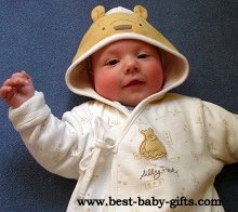 cute baby in a hooded Winnie The Pooh jumper, the hood has bear ears and a bear face