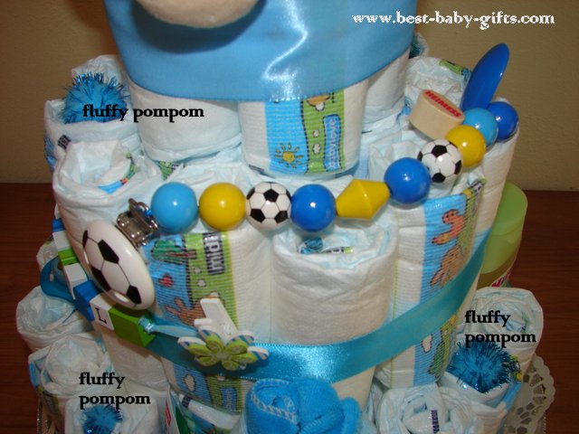 details of the diaper cake on the left side, pacifier chain with soccer balls attached to the cake