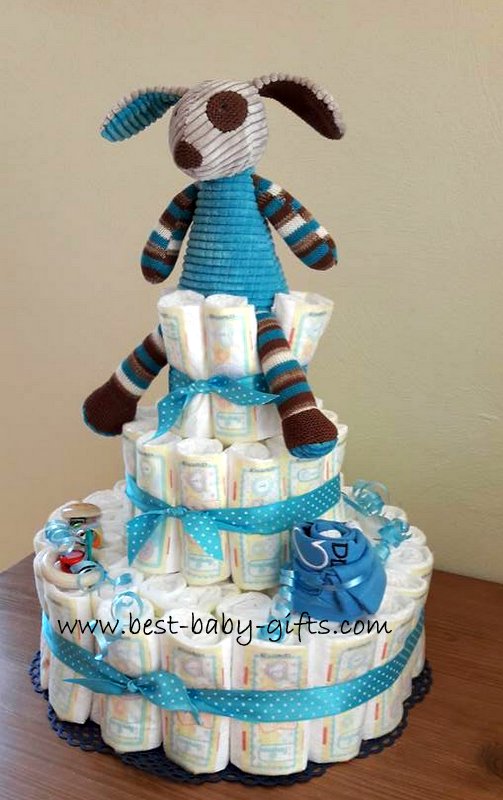a traditional 3 tier diaper cake with a dog plush toy on top, blue colors