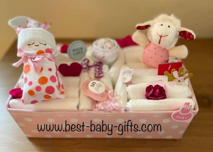 a pink polka dot box filled with diapers, a diaper baby and a little cuddly sheep as well as other baby girl decoration