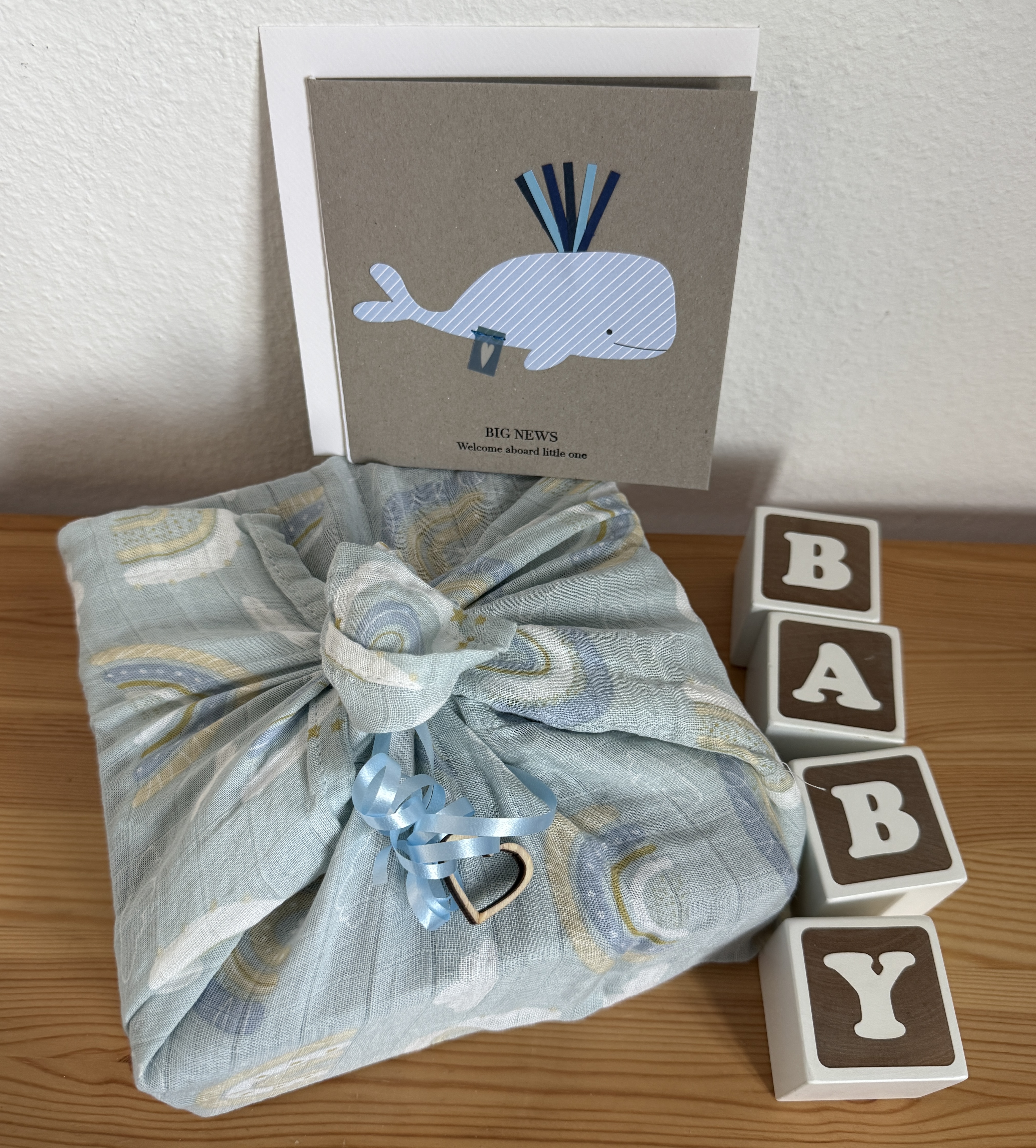 sustainable baby gift wrap: a baby gift wrapped in a blue burp cloth with rainbow design