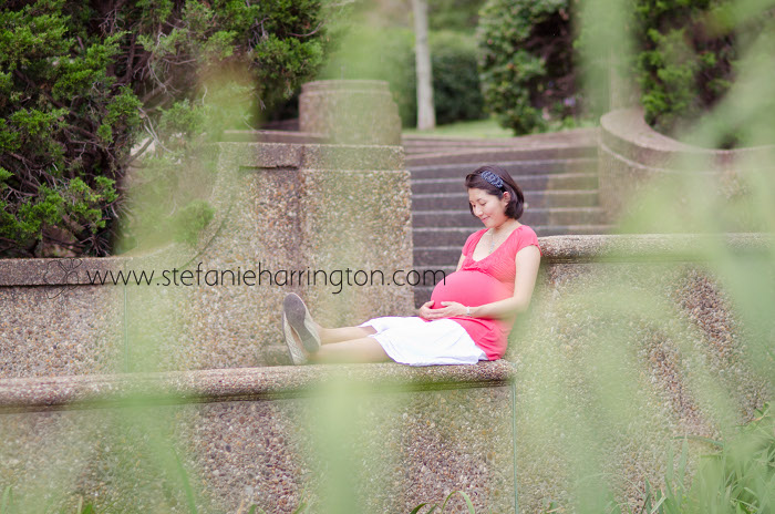 a mom-to-be relaxing at a park and looking at her baby belly
