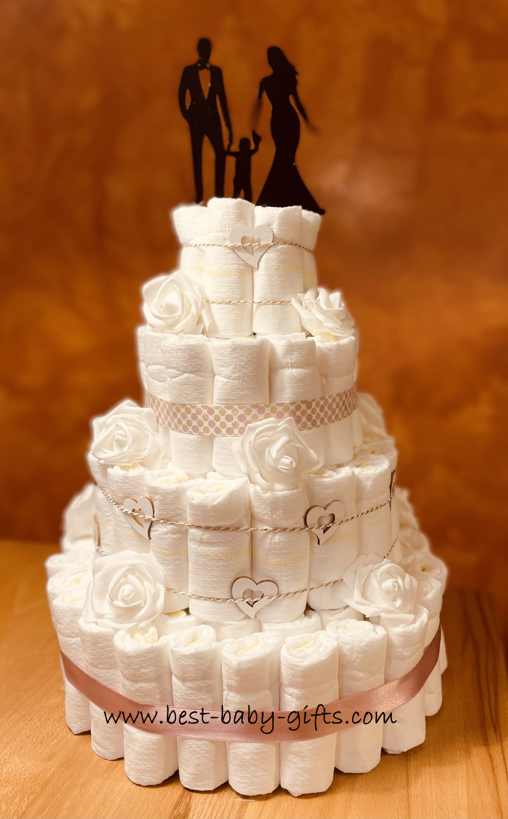 a modern 4 tier diaper cake with a wedding couple and baby on top