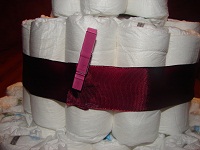 Windeln mit dunkelrotem Schmuckband und Klammer um das Band zu halten